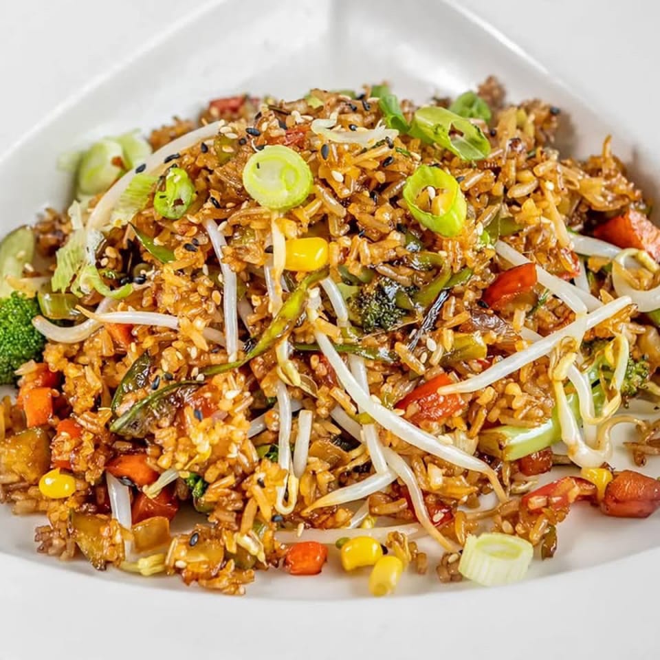 Vegetable fried rice topped with scallions and sesame seeds.