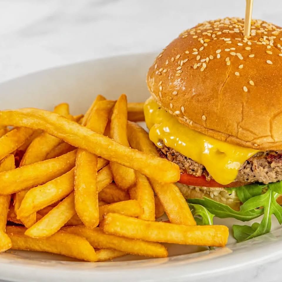 Burger with melted cheese, greens, and fries.