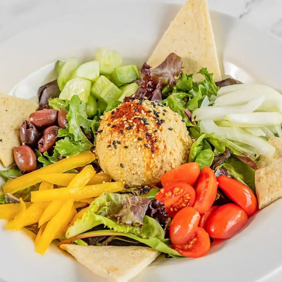 Hummus salad with cucumber, tomatoes, olives, peppers, and pita.